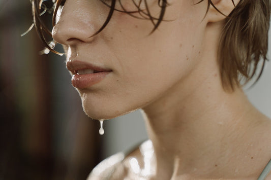 Femme avec de légères gouttes de transpiration au menton, illustrant les causes naturelles de la transpiration